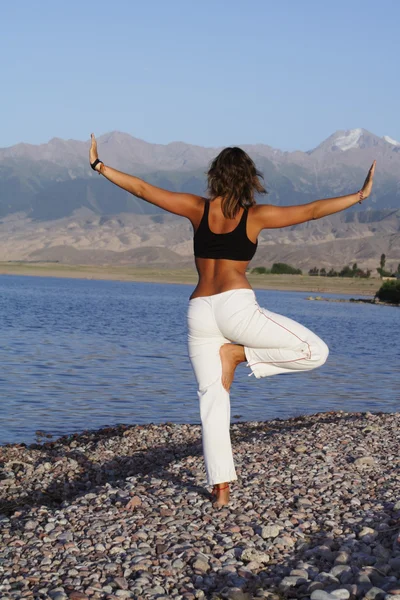 Schoonheid meisje in yoga vormen op strand — Stockfoto