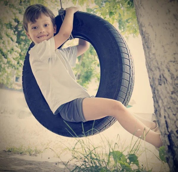 Menino feliz no balanço ao ar livre — Fotografia de Stock