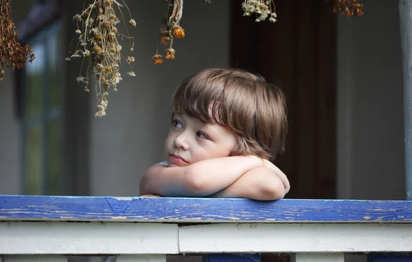 Triste bambino sotto il portico della casa rurale — Foto Stock