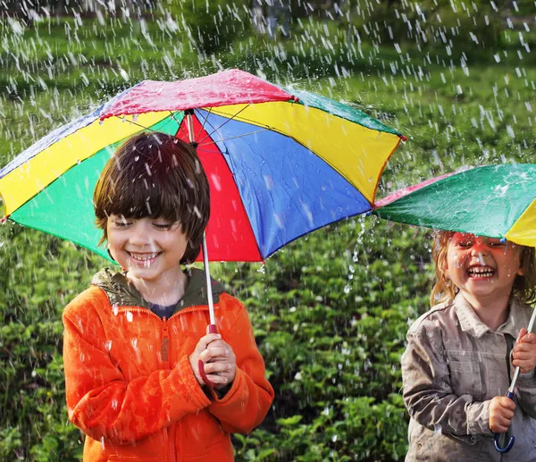 Açık havada şemsiye ile mutlu iki kardeş — Stok fotoğraf