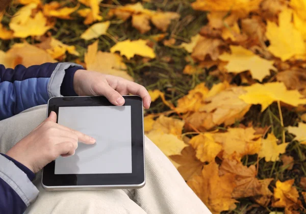 Adolescente utiliza una tableta en el parque de otoño — Foto de Stock