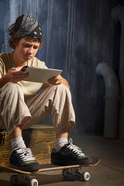 Tinédzser ül a gördeszka, tábla-PC — Stock Fotó