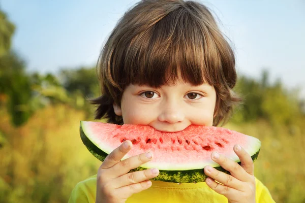 Criança feliz comendo melancia no jardim — Fotografia de Stock