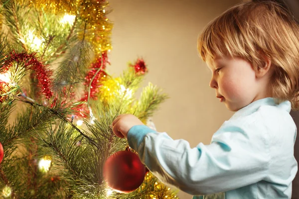 Boy hangs Christmas toy — Stock Photo, Image