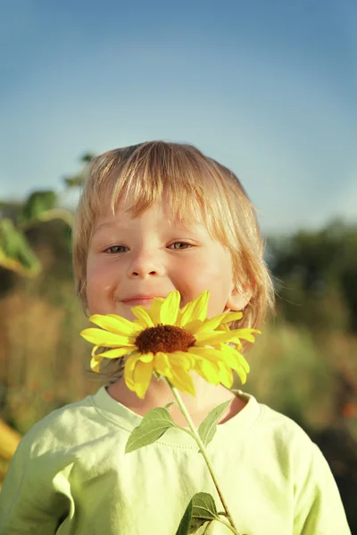 Gelukkige jongen met zonnebloem buitenshuis — Stockfoto