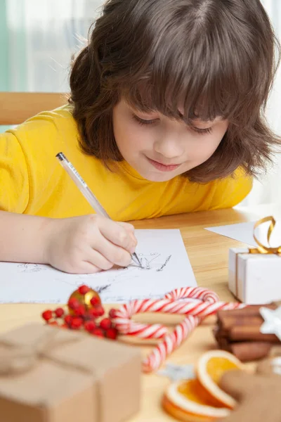 少年はサンタクロースへの手紙を書く クリスマスツリーの近くだ メリークリスマスとハッピーホリデー — ストック写真