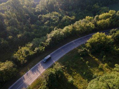Ormandaki otoban üzerindeki hava manzarası. İnsansız hava aracı görüntüsü. Yaz zamanı araba havadan doğaldır. Hava görünümü.