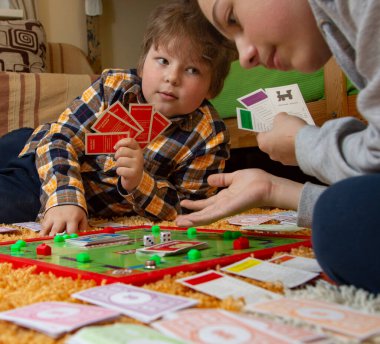 Belgorod, Rusya - APR, 20, 2020: Çocuklar yerde Scrabble oynuyor. Masa oyunu çipleri bulmacada gizlidir. Eğitim, eğlence konsepti
