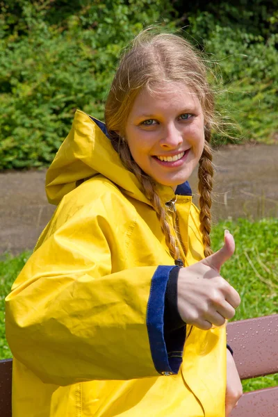 Młoda Uśmiechnięta Kobieta Żółtym Płaszczu Przeciwdeszczowym Kciuku Góry — Zdjęcie stockowe