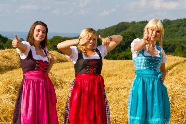 Dirndls 'de üç kız, başparmak yukarıda.