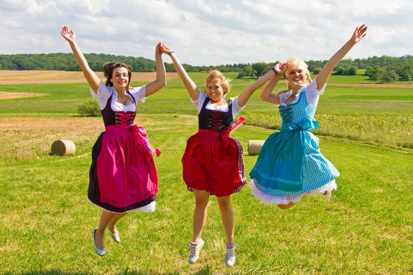 Three Happy Girls Dirndls Jumping Meadow —  Fotos de Stock