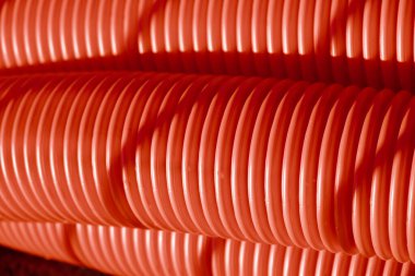 Red corrugated plastic tubes. Industrial background. Products from plastic. Drainage and sewerage. Urban network.