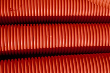 Red corrugated plastic tubes. Industrial background. Products from plastic. Drainage and sewerage. Urban network.
