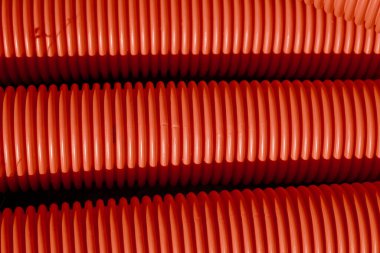 Red corrugated plastic tubes. Industrial background. Products from plastic. Drainage and sewerage. Urban network.