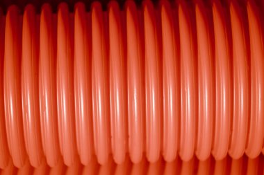 Red corrugated plastic tubes. Industrial background. Products from plastic. Drainage and sewerage. Urban network.