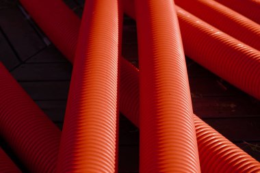 Red corrugated plastic tubes. Industrial background. Products from plastic. Drainage and sewerage. Urban network.