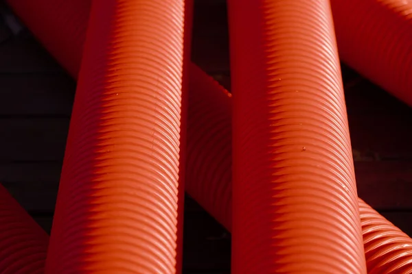 Red corrugated plastic tubes. Industrial background. Products from plastic. Drainage and sewerage. Urban network.
