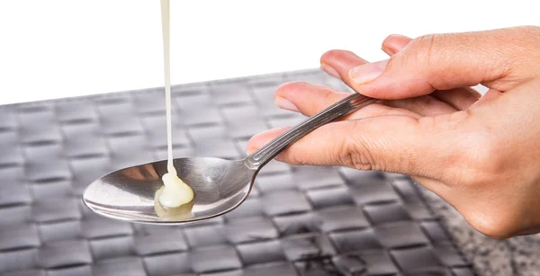 Cream pouring onto a spoon i — Stock Photo, Image