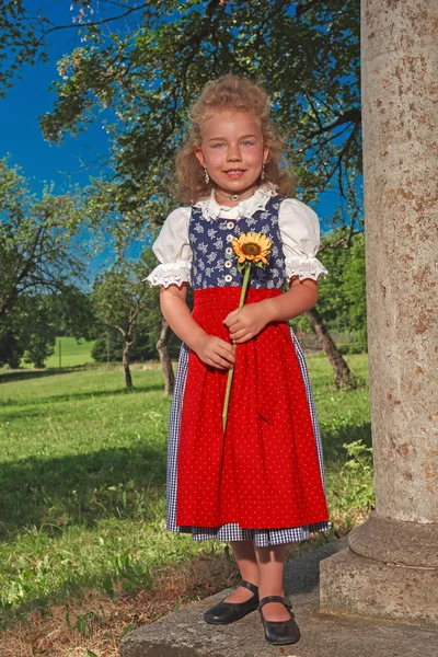 Маленькая баварская девочка в грязи с подсолнухом — стоковое фото
