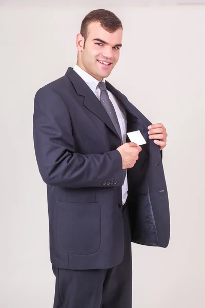 Улыбающийся бизнесмен вытаскивает визитку из пиджака — стоковое фото
