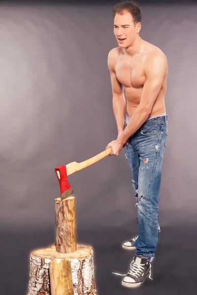 Muscular young man chopping logs — Stock Photo, Image