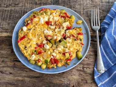 Kahvaltı için ahşap masada ev yapımı sebzeli ve peynirli omlet.