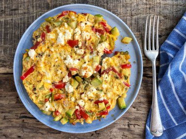 Kahvaltı için ahşap masada ev yapımı sebzeli ve peynirli omlet.
