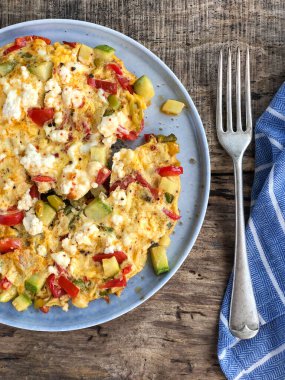 Kahvaltı için ahşap masada ev yapımı sebzeli ve peynirli omlet.