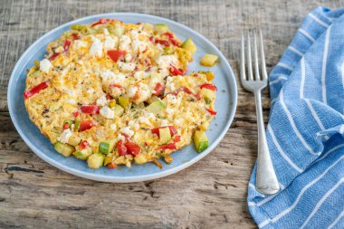 Kahvaltı için ahşap masada karışık sebzeli ve peynirli omlet yakın plan.