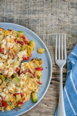 Kahvaltı için ahşap masada karışık sebzeli ve peynirli omlet yakın plan.