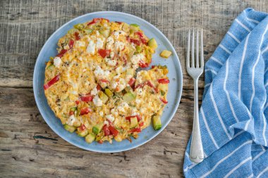 Kahvaltı için ahşap masada karışık sebzeli ve peynirli omlet yakın plan.