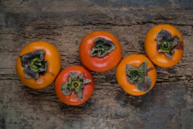 hurma meyvesi, ahşap arka planda veya yüzeyde seçici odak ve gürültü efektleriyle Asya veya Karadeniz hurma meyvelerinin üst görünümü