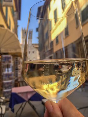 İtalya, Toskana 'da seçici odaklı köpüklü şarap ya da Prosecco camından binalara ve sokak manzarasına bakmak. İtalyan içkisi ve İtalya gürültü efektli seyahat kavramı