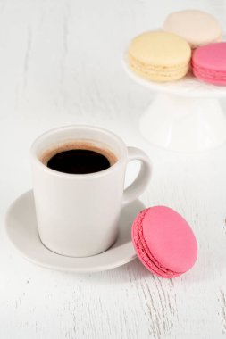 Makaronlar, kahve, renkli badem kurabiyeleri ve ahşap masada bir fincan kahve. Ahşap arka planda lezzetli Fransız kurabiyeleri