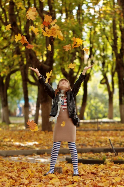 Щаслива маленька дівчинка грає з осіннім листям у парку — стокове фото
