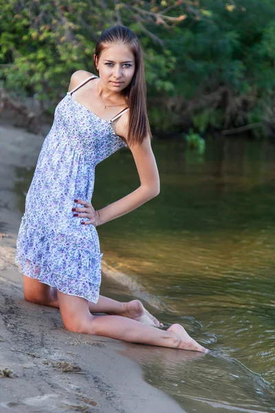 Mujer joven arrodillada en la playa — Foto de Stock