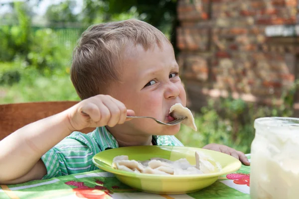 Boy eats breakfast outdoors — Stock Photo, Image