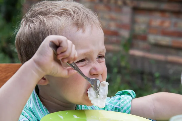 Boy eats breakfast outdoors — Stock Photo, Image