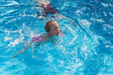 Çocuk havuzda yüzüyor.