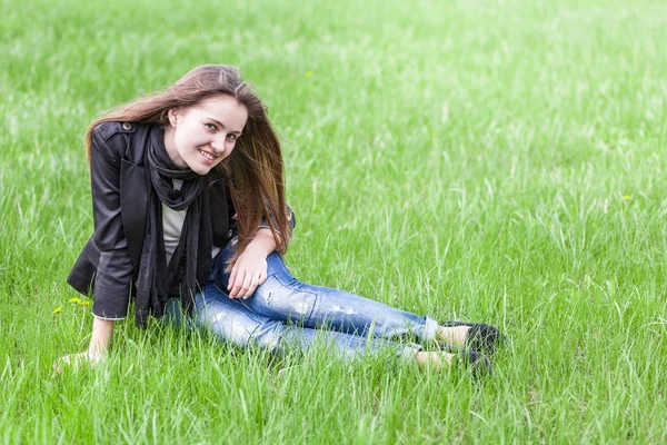 Young woman sits on lawn — Stock Photo, Image