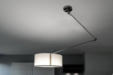 Odanın tavanında modern bir lamba var.