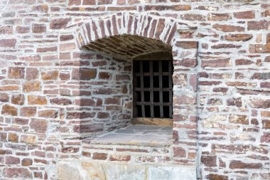 Loophole with bars in the fortification wall of a medieval castle, outside view