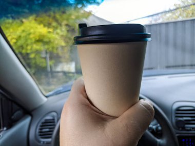 Arabada nefis aromatik kahve var. Fincanı arabaya koy. Elde bardak. Kahveli şoför. Yolculukta bir bardak ve bir içki. Milkshake arabada. 