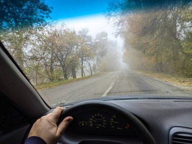 Şoför araba kullanıyor. Kötü bir yolda araba kullanmak. Camı kır. Tehlikeli bir yol. Sisteki arabanın kontrolü. Sis ve yol. Islak bir yolda araba.. 