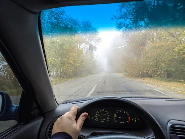 开车的司机 在一条糟糕的路上开车 玻璃上的裂缝 危险的道路 在雾中控制汽车 雾和道路 湿路上的汽车 — 图库照片