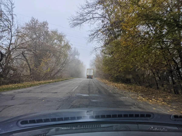 开车的司机 在一条糟糕的路上开车 玻璃上的裂缝 危险的道路 在雾中控制汽车 雾和道路 湿路上的汽车 — 图库照片