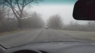 Şoför araba kullanıyor. Kötü bir yolda araba kullanmak. Camı kır. Tehlikeli bir yol. Sisteki arabanın kontrolü. Sis ve yol. Islak bir yolda araba.. 