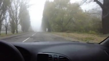 Şoför araba kullanıyor. Kötü bir yolda araba kullanmak. Camı kır. Tehlikeli bir yol. Sisteki arabanın kontrolü. Sis ve yol. Islak bir yolda araba.. 
