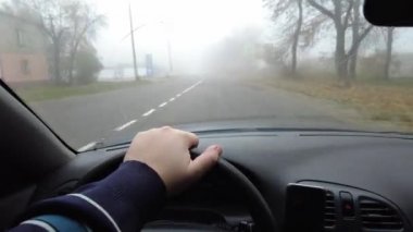 Şoför araba kullanıyor. Kötü bir yolda araba kullanmak. Camı kır. Tehlikeli bir yol. Sisteki arabanın kontrolü. Sis ve yol. Islak bir yolda araba.. 
