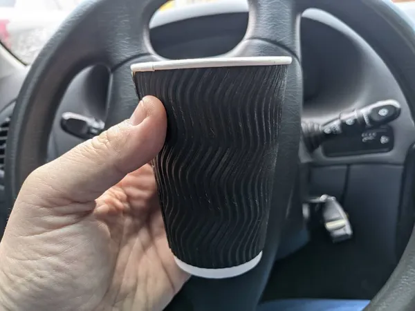 車の中でフロスとおいしいコーヒー 車の運転手がコーヒーを飲みます 旅行コーヒー 車のサロンでミルクセーキ カプチーノと泡をガラスに入れて — ストック写真
